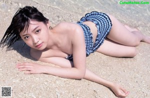 A woman in a black and white bikini sitting on a beach.