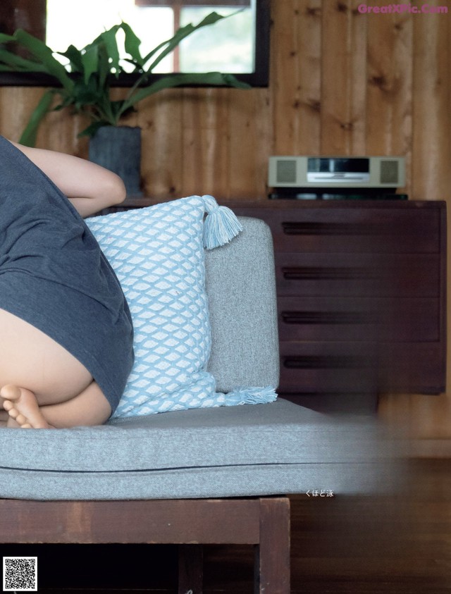 A woman laying on a couch with her back to the camera.