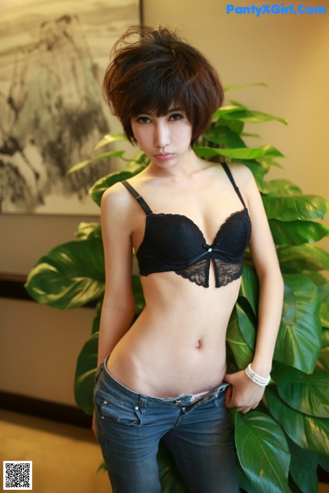 A woman in a black bra and jeans posing for a picture.