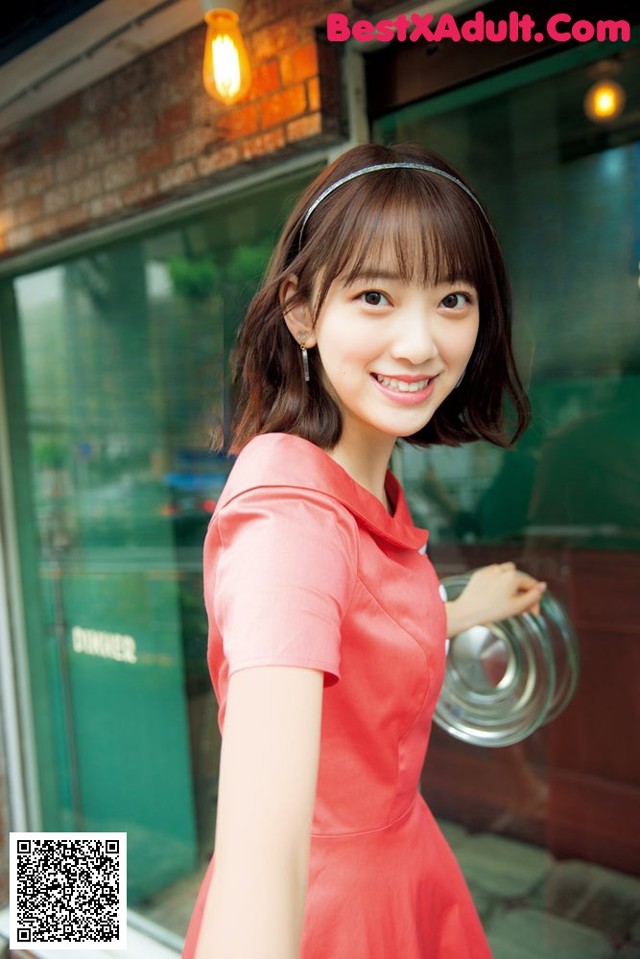 A woman in a red dress standing in front of a store.