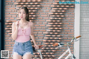 A woman in a pink top and denim shorts posing for a picture.