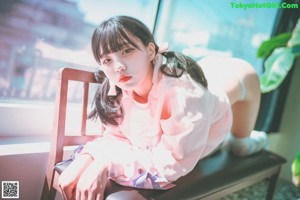 A woman in a pink sweatshirt and blue stockings posing on a swing.