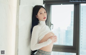 A woman in a white shirt is posing on a bed.