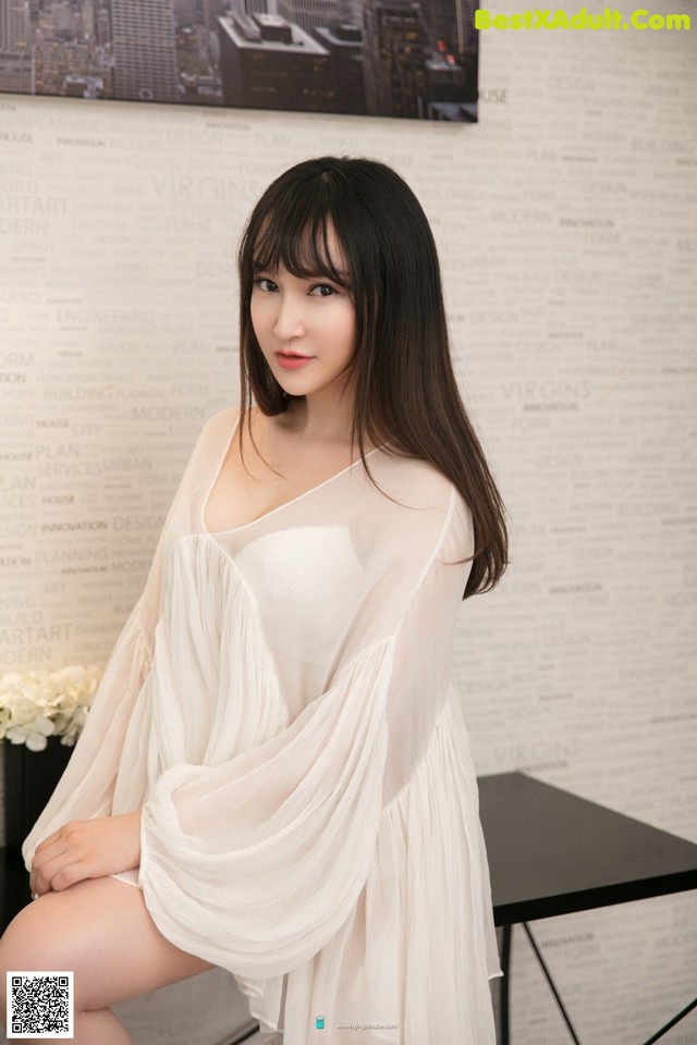 A woman in a white dress sitting on a table.