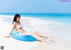 A woman in a blue bikini laying on a bed.