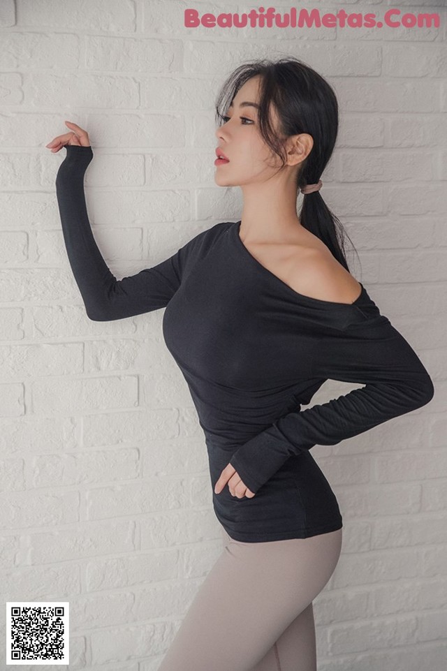 A woman in a black top and gray tights posing for a picture.