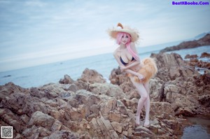 A woman in a bikini standing on a rocky beach.