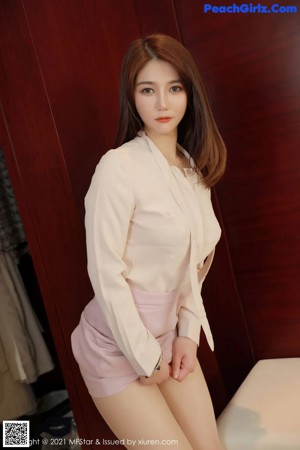 A woman in a white shirt and pink skirt posing for a picture.