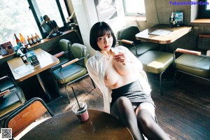 A woman standing in front of a bar holding a glass.