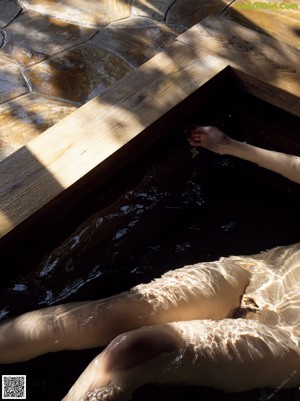 A naked woman sitting in a hot tub in the water.