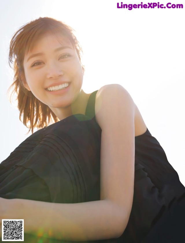 A woman in a black dress smiles at the camera.