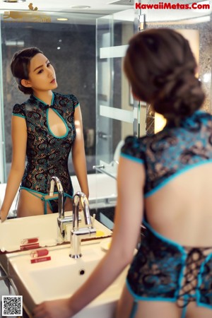 A woman in a blue and black lingerie sitting on a bathroom counter.