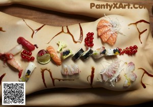 A naked woman laying on a wooden floor covered in sushi.