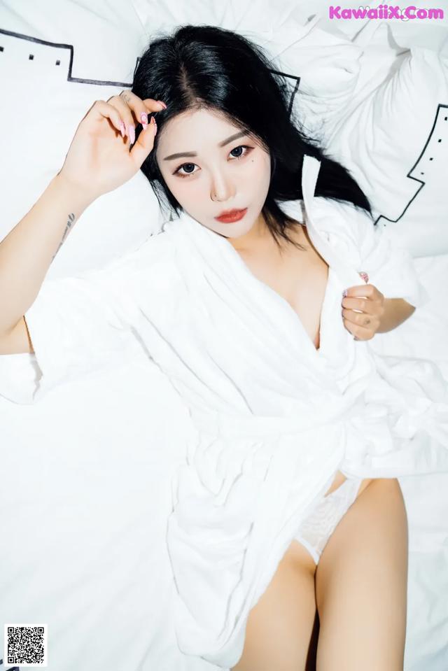 A woman in a white robe laying on a bed.