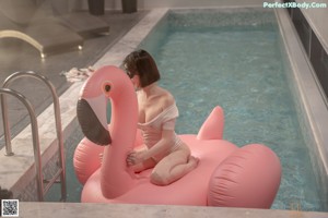 A woman in a white bodysuit sitting on an inflatable pool float.